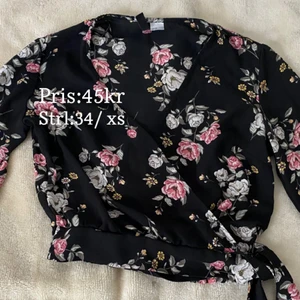 Blommig omlott skjorta med knytband - En fin blommig omlott skjorta/bluse med knytband om sidan . I storlek xs , köpt från hm, säljes för endast 45kr 
