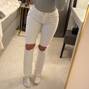 Vita utsvängda jeans från madlady - Vita utsvängda jeans köpta på madlady med hål på knäna. Storlek 34, stretchiga jeans som sitter väldigt skönt. Sitter ganska lågmidjat. Säljes för 120 kr + frakt 