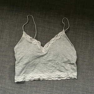 Grå padded topp - Grå padded topp med vita spetsdetaljer i storlek S från H&M. Perfekt till sommarn! Frakt ingår ej i priset för plagget!