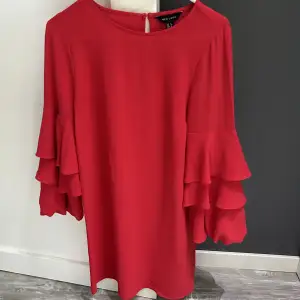 Klänning från new look i häftigt röd färg och volanger på armarna. Använd bara en gång, bekväm och normal i storlek.