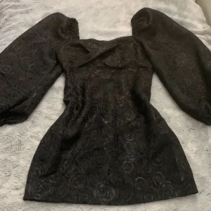 Fest klänning  - En svart fin klänning med ett ros-mönster. Passar inte mig därav säljer den. Nyskick! Köpare står för frakt. (Pm för fler bilder)