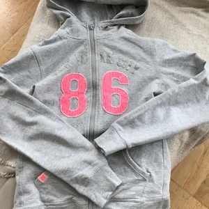 86 huvtröja/hoodie - Snygg tröja med luva och dragkedja grå och det står 86 med stora rosa siffror💘 Älskar denna men jag har vuxit ur den