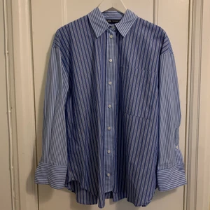 Zara skjorta båvit - Skjorta från Zara, blå-vitrandig och rutig i olika block. Köpt av min syster som köpte två olika storlekar och valde den andra, men jag har aldrig använt denna så den är helt ny. 100% bomull. 