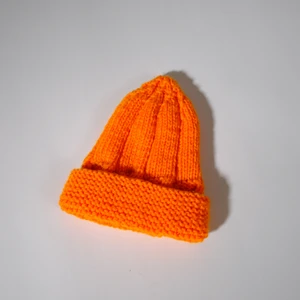 Stickad orange mössa  - One-of-a-kind orange stickad mössa. Stickad av Röda Korsets-stickgrupp i Västerort tillsammans med Ebba Martin. Alla pengar från budgivningen går oavkortat till Röda Korsets arbete för att hjälpa människor i kris och katastrofer.