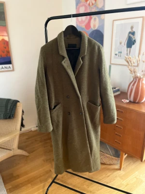 Grön kappa  - Grön lång kappa från monki. Använd 1 säsong men i gott skick. Storlek M men passar även S. Säljs fortfarande k andra färger. Produktbild sista bilden. 