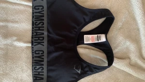 2 st gymshark sportbhar - Helt ovanvända sport-bhar från gymshark, säljs pga passar ej mig. Väldigt små i strl så passar mer en S/XS. Modellen på båda är samma men färgerna är olika, den ena är grå och den andra svart! 150kr/styck. Köparen står för frakten!