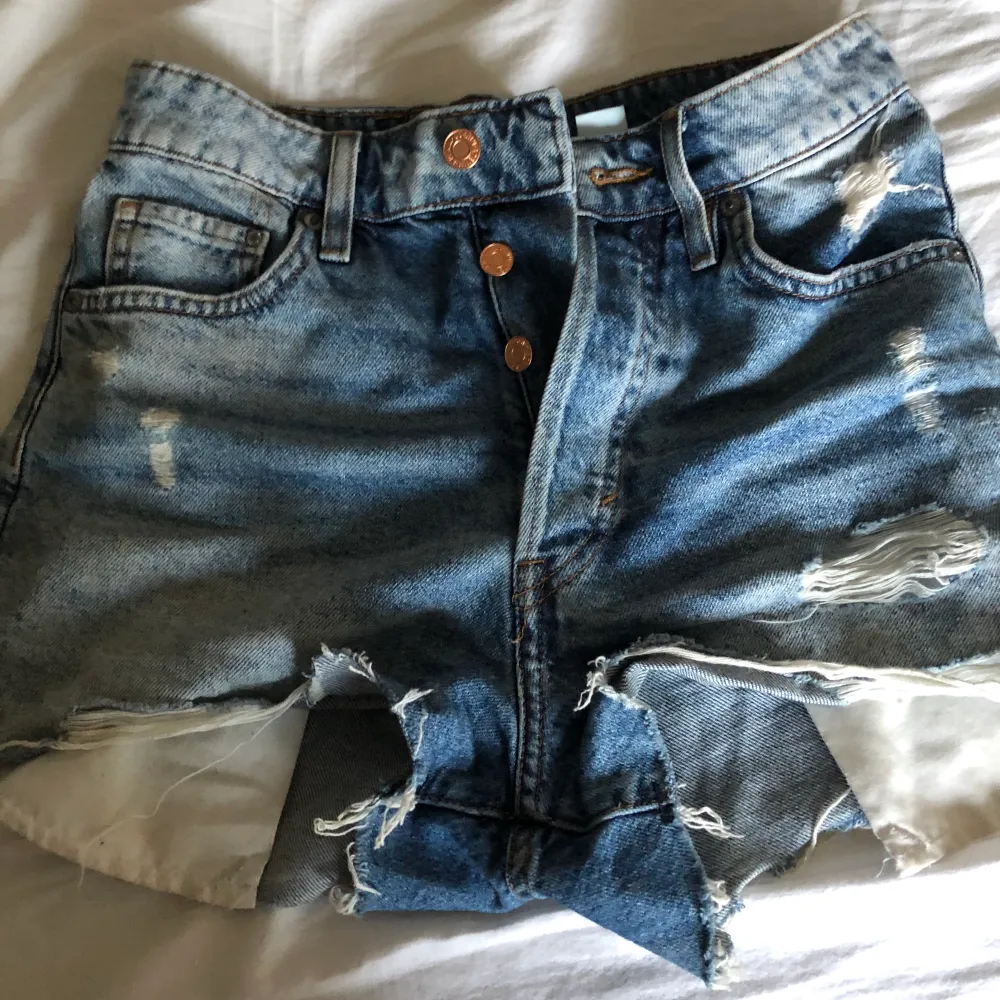 Jeans shorts i färgen blå, något slitna men inget som märks i kvaliteten, hög midja, dem har knappar istället för en gylf, väldigt sköna.. Shorts.