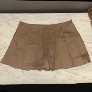 Veckad minikjol brun - Brun veckad minikjol i nysnick. Den har ”innbygda” skjorts. Praktisk och väldigt söt men är tyvärr alldeles för liten för mig. Köpt i storlek L men väldigt liten i storleken så skulle snarare säga att den är S/M. Frakt ingår i priset.