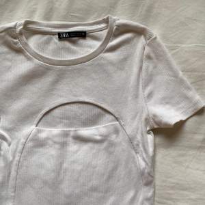 En vit t-shirts med ett hål på mitten av tröjan som detalj, inte använd mer än 5 gånger! 🫶🏼