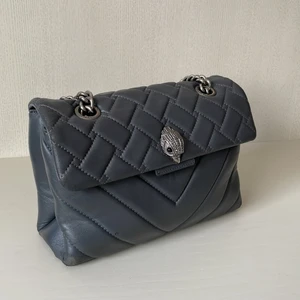 Kurt Geiger väska - Säljer min älskade Leather Kensington Bag från Kurt Geiger i färgen GREY. Väskan är ”normalstor” och rymmer det mesta, måtten är 180x265x80 mm. Tyvärr har väskan några små skador i kanterna, jag kan skicka bilder om ni vill!😙💕🔥                                                      