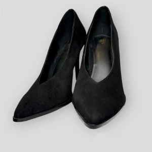 Black shoes  - Court shoes in soft suede with pointed toes and covered heels. Linings in satin made from recycled polyester, and leather insoles. Heel 7 cm.  