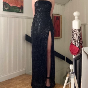 Svart Glittrig långklänning  - Fin svart långklänning med glittriga paljetter som är strapless med en slit. Aldrig använt utan bara testat hemma.