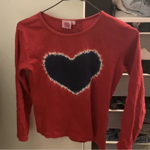 Tiedye tröja - En röd långärmad tröja med tiedye blå och vit, och pärlor runt om. Storlek m/s skulle jag säga men passar mindre storlekar även. Står ej för frakten!