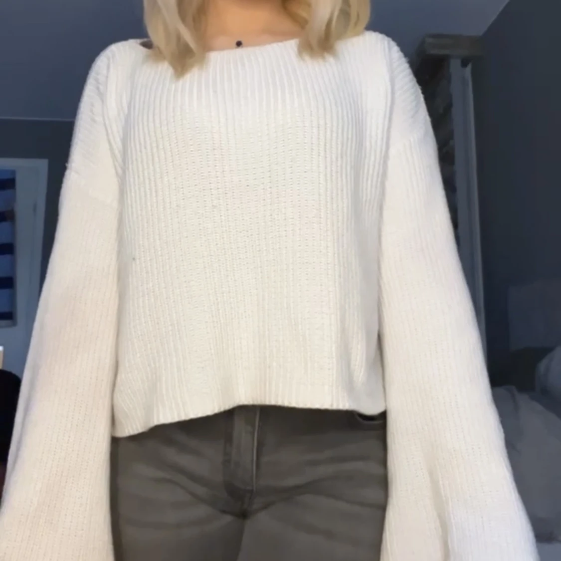 Vit stickad tröja med utvängda armar 