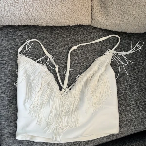 Söt top med fransar  - Urringad Crop top med fransar. Justerbara axelband. 