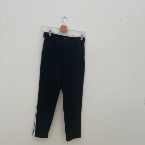 Kostymbyxor - Svarta kostymbyxor med vit revär från Vero Moda, strl S