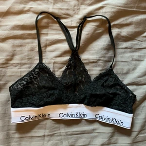 Calvin Klein topp - Säljer en topp/bh ifrån Valvin Klein. Den är svart med spetsmönster.  Första bilden är framifrån och andra bakifrån.