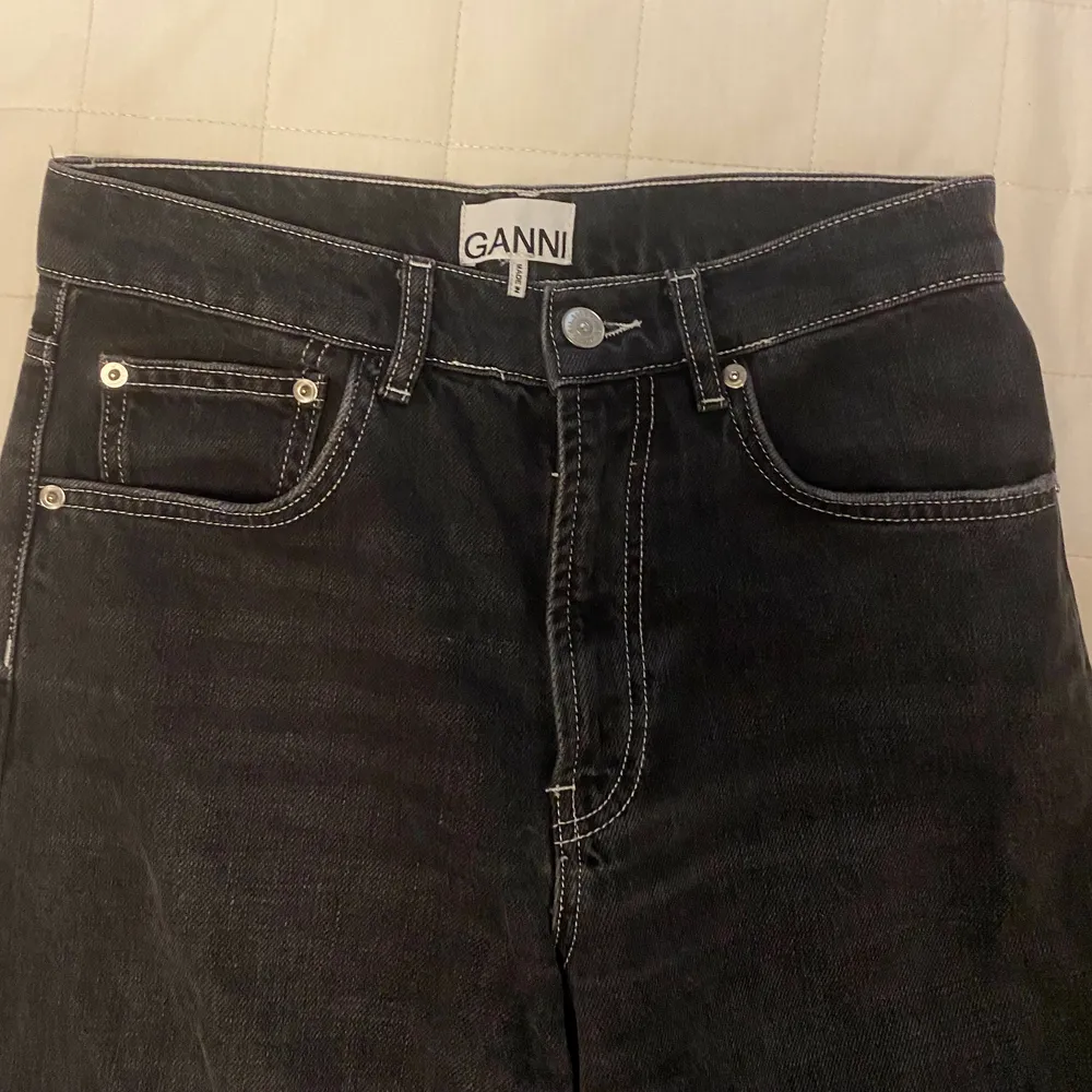 Skitsnygga utsvängda svarta jeans från GANNI! Köptes förra året, men tyvärr inte kommit till användning så jeansen är i nyskick! Coola vita sömmar och GANNI märket gör jeansen väldigt unika! Storlek 26/32, nypris: 1800kr. Jeans & Byxor.
