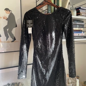 Den lilla svarta! Paljetter - Oanvänd klänning från NLY. Öppen supersnygg rygg!  Gick upp i vikt under tiden den hängde i garderoben under pandemin i väntan på fest. Passar därmed inte mig längre och den söker ett nytt hem! 