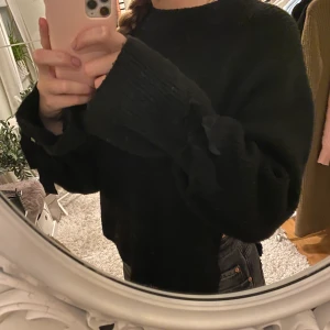 Tröja med rosetter - Säljer denna svarta tröja som är öppen vid sidan; samt har rosetter vid ärmen. Storlek S