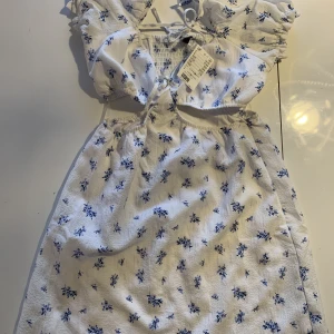 Ny hm klänning  - Helt ny lappen kvar. Nypris 199kr.  Vit klänning med blåa blommor på 