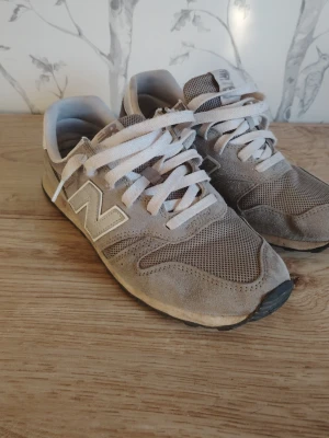Beige New Balance 373 sneakers - Snygga beige New Balance 373 sneakers med klassisk mesh och mocka på ovandelen. Skorna har vita snören, ikoniska N-loggan på sidan och en låg siluett som passar till det mesta. Perfekta för dig som gillar stilrena och bekväma sneakers.