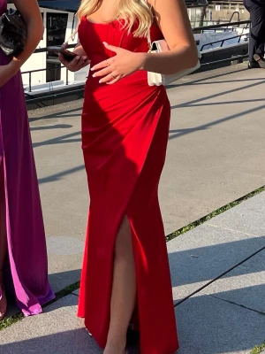 Balklänning Röd - Har nu bestämt mig för att sälja min balklänning då den tyvärr inte kommer till användning. Den är endast använd en kväll och har inga defekter. Man får med axelband som ligger i fickan på sista bilden. Köpte den helt ny för 1800:-✨