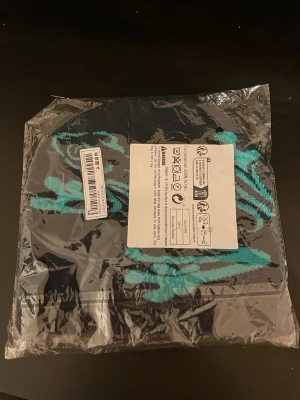 Svart mössa med turkos groda - En snygg mössa som är jätte mjuk och passar perfekt för våren