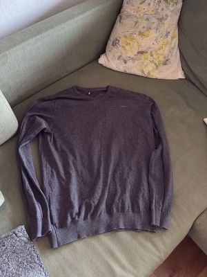 Mörkgrå stickad tröja Hampton Republic - Snygg mörkgrå stickad tröja från Hampton Republic i storlek M. Tröjan har rund halsringning, långa ärmar och ribbade muddar vid ärmslut och nederkant. Perfekt basplagg i mjukt material som passar till det mesta.