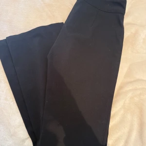 Svarta kostymbyxor från Nelly - Snygga svarta kostymbyxor från Nelly i storlek 32. Byxorna är bootcut med låg midja