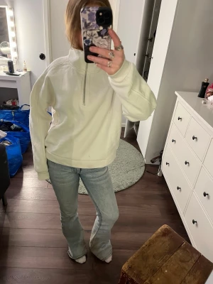 Vit halvzip sweatshirt med hög krage - Säljer en oversized vit sweatshirt med halvzip och hög krage. Tröjan har långa ärmar och en avslappnad passform, perfekt för en chill och stilren look. Materialet känns mjukt och bekvämt, perfekt att slänga på sig till jeans eller leggings. Finns dock ett litet hål på baksidan av höger arm
