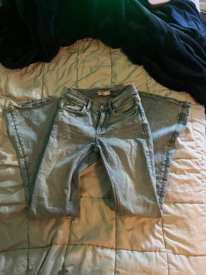 Ljusblå bootcut jeans - Säljer ett par ljusblå bootcut jeans med klassisk femficksdesign och dragkedjegylf. Jeansen har en avslappnad passform med utsvängda ben och är tillverkade i denim. Perfekta för en chill och trendig look.