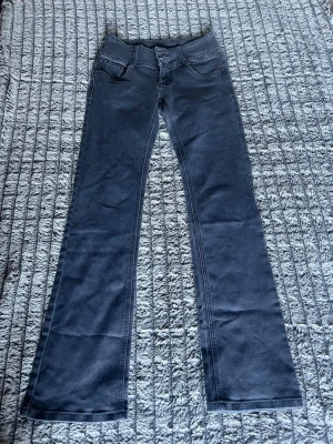 Gråa low waist y2k bootcut jeans - Snygga mörkgråa bootcut jeans med låg midja. Tjockt waistband med 3 knappar. Jeansen har lätt stretch och midjemåttet är 33cm (66cm) och innerbenslängden är 81cm. 