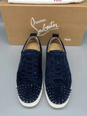 Svarta Louboutin sneakers med nitar - Snygga svarta sneakers från Christian Louboutin med mattsvarta nitar på tån och vit sula. Skorna har en klassisk låg siluett, snörning och är tillverkade i mocka för en lyxig känsla. Perfekta för dig som vill sticka ut med din stil.