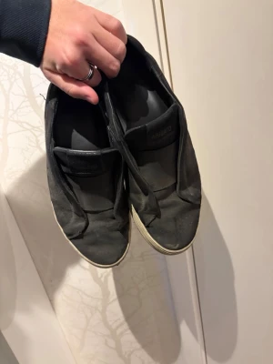 Svarta slip-on sneakers från Axel Arigato - Svarta slip-on sneakers från Axel Arigato med minimalistisk design. Ovandelen är i tyg och sulan är vit och något tjockare. Inga snören, enkel att ta på och av. Passar perfekt till en clean och avslappnad stil. Säljs billigt som fan tack vare slitheten. Vid mer frågor eller info skriv gärna! ABS! Pris gpr att diskutera! 