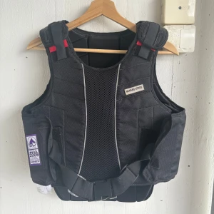 Perfekt julklapp till den ridintresserade  - Svart ridväst Hansbo Sport - Svart säkerhetsväst (ridväst) från Hansbo Sport, modell med justerbara axelremmar och midjebälte. Snygg och funktionell design. Använd under 5 gånger. Tydligare storleksbeskrovning finns på bild 4 och 5. Västen kommer inte till användning. Priset går att diskuteras vid snabb affär💗