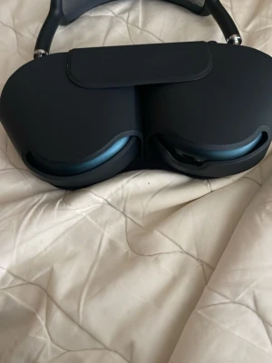 Apple AirPods Max hörlurar blå - Snygga over-ear hörlurar från Apple i blå färg med matchande skyddsfodral. Hörlurarna har en modern design med mjuka öronkuddar i tyg och metallbåge. Perfekta för dig som vill ha grymt ljud och stilren look.