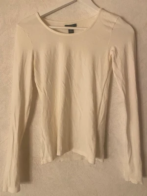 Vit långärmad topp - En enkel och stilren vit långärmad topp från Newyorker. Modellen har rund halsringning och är figurnära i passformen. Perfekt att matcha med jeans eller kjol för en clean look.