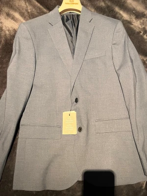 Ljusblå kavaj från H&M - Helt ny snygg kavaj från HM i slimfit. Kavajen är som sagt aldrig använd och nyss pris ligger på 799kr. Priset som jag lagt är ej hugget i sten så här jättegärna av dig om du har frågor kring kavajen!