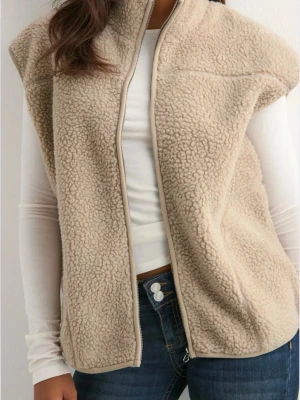 Beige teddyväst med dragkedja - Mysig beige teddyväst med hög krage och dragkedja framtill. Den är väldigt värmande skulle jag säga och man får plats med en tröja under den troligen en hoodie också. 