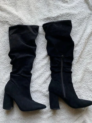 Svarta stövlar  - Säljer ett par svarta slouchy stövlar med hög klack och spetsig tå. Stövlarna är i mjukt mockaimitationsmaterial och har dragkedja på insidan. Perfekta till kjol eller klänning för en trendig look. Superbra skick! Storlek 36! 