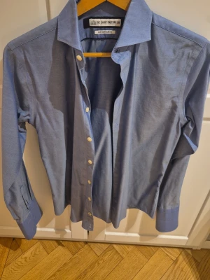 Blå skjorta från The Shirt Factory - Klassisk blå skjorta från The Shirt Factory med lång ärm, vit knappstängning och dubbelvikta manschetter flr manchettknapp