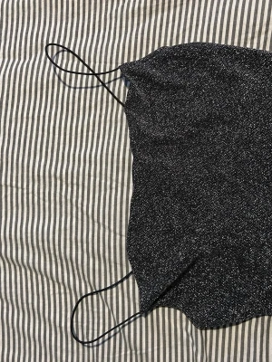 Glittrig svart linnetopp med tunna band - Snygg svart linnetopp med glittrigt tyg och tunna axelband. Perfekt för dig som vill sticka ut lite extra. Toppens material känns mjukt och följsamt mot huden.