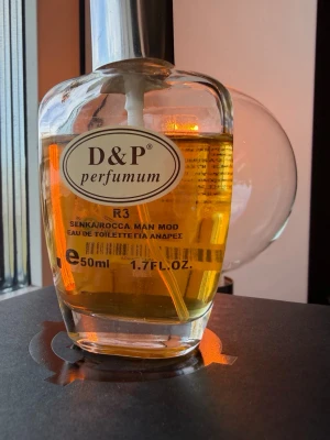 D&P Perfumum R3 Eau de Toilette 50ml - D&P Perfumum R3 är en eau de toilette för män med en fräsch och maskulin doft. Flaskan är genomskinlig med rundade former och har en silverfärgad spraykork. Parfymen är gyllengul och flaskan rymmer 50 ml. Perfekt för dig som gillar stilrena och klassiska dofter.