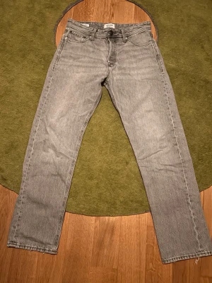 Jeans från Jack & Jones 29/32 - Snygga grå jeans från Jack & Jones i relaxed fit med raka ben. Klassisk femficksmodell och knappgylf. Perfekta för en avslappnad stil och tillverkade i bomull för skön komfort.