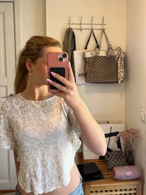 Leopardmönstrad t-shirt från Lindex - Säljer en vit och beige t-shirt från Lindex med leopardmönster. T-shirten är kortärmad och har en lätt croppad passform. Perfekt för dig som gillar trendiga och djurmönstrade plagg.