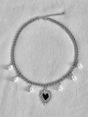 Silverfärgat halsband med pärlor och hjärta - Ett chunky silverfärgat halsband med sex vita pärlor och ett stort svart hjärtformat hänge med detaljerad ram. Kedjan är grov och justerbar, och hänget har en vintage-inspirerad design. Perfekt för att ge din outfit en cool och unik touch.