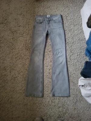 Grå bootcut jeans från 157 - Snygga grå jeans från 157 med bootcut-modell och låg midja. Jeansen har klassisk femficksdesign och är tillverkade i denim. Perfekta för dig som gillar en avslappnad men trendig stil.