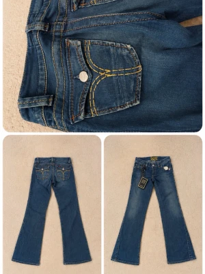 Blå bootcut jeans från GOS - Snygga blå bootcut jeans från GOS med kontrasterande gula sömmar och klassiska fem fickor. Jeansen har låg midja och utsvängda ben, perfekt för en trendig och avslappnad look. Metallknapp och detaljerade bakfickor ger extra stil. 158-165