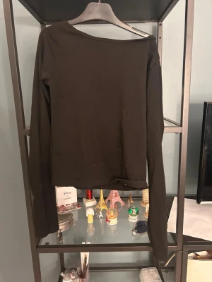 Svart långärmad topp med öppen rygg - En svart långärmad topp med öppen rygg och enkel design. Toppen har en rak passform och är tillverkad i ett mjukt material som känns skönt mot huden. Perfekt att styla med jeans eller kjol för en clean look.